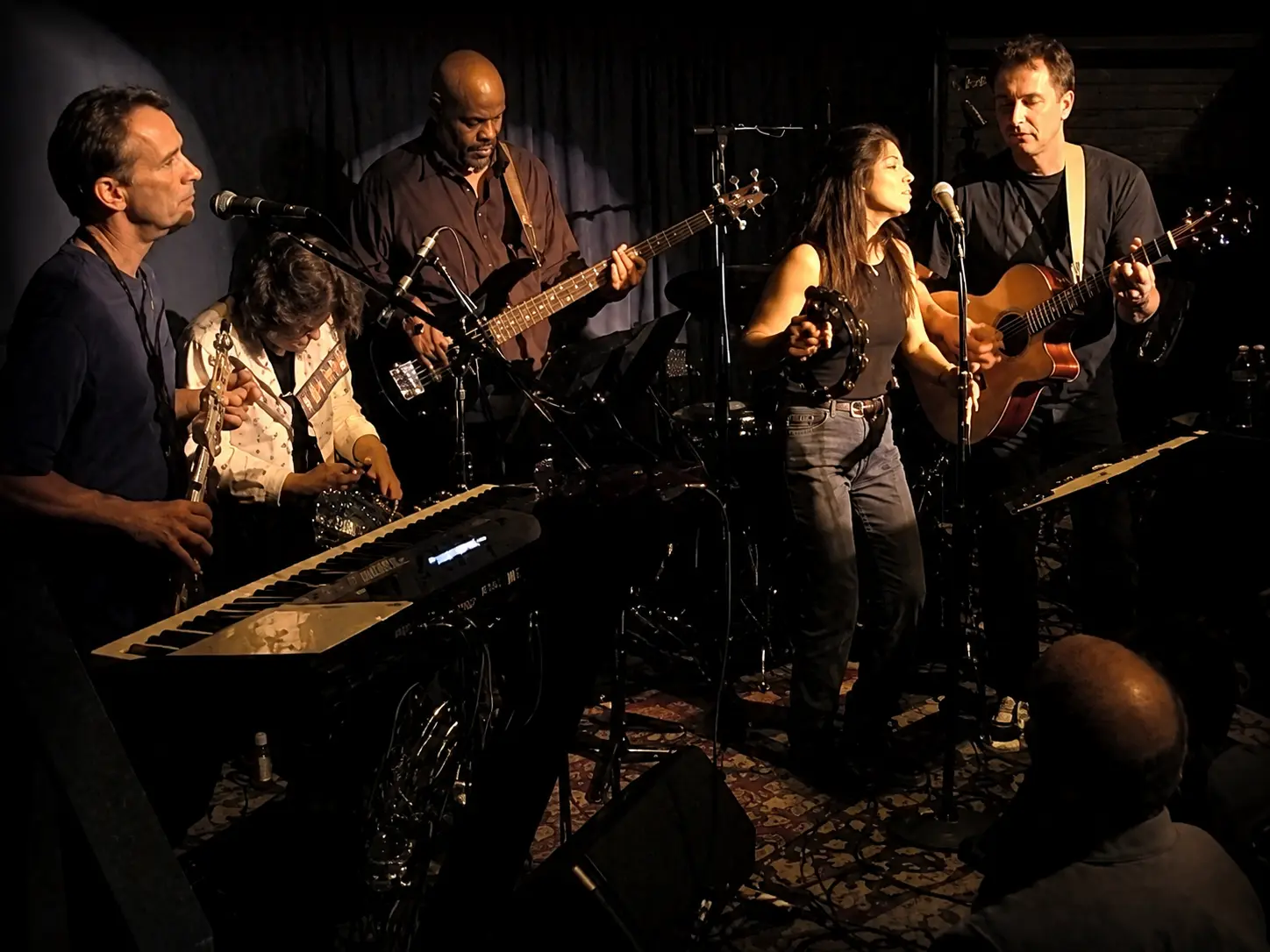 A four-piece band performing together in an intimate indoor setting